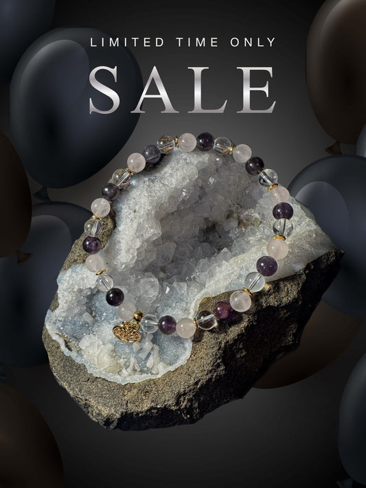 Bracelet en Quartz Rose, Améthyste et Cristal de Roche, sublimé par un pendentif arbre de vie doré. Il repose sur un cristal brut, créant une ambiance élégante et mystique.